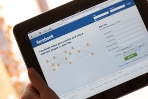 Hands holding ipad with facebook on the screen