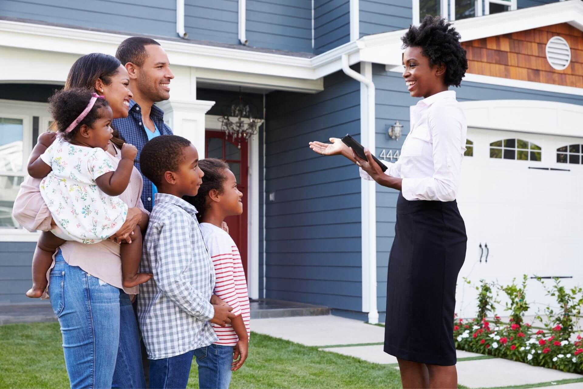 Black family and real estate agent talking infront of house